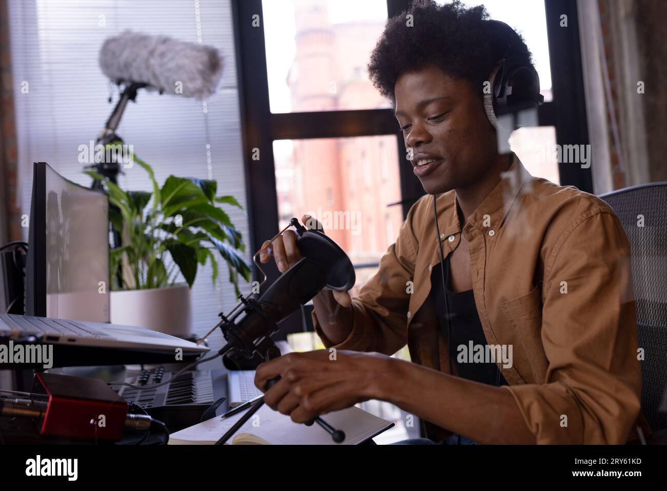 Felice uomo afro-americano con cuffie che realizza podcast dal vivo utilizzando il microfono a casa, copia spazio Foto Stock