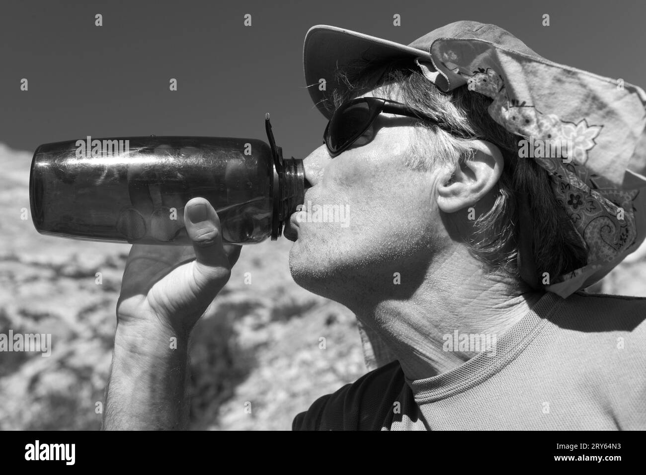 Un uomo maturo che beve da una bottiglia d'acqua. Foto Stock