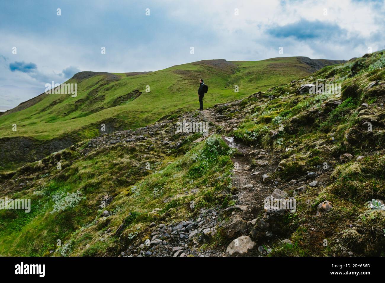 Uomo su una montagna ricoperta di erba verde con un'avventura nel cielo blu Foto Stock