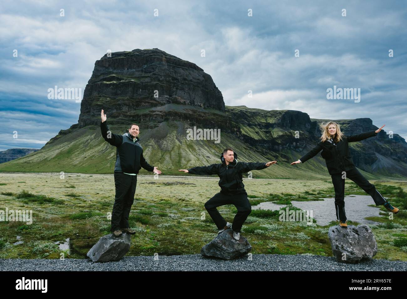 Gli amici posano su massi di fronte alla verde montagna con le nuvole Foto Stock