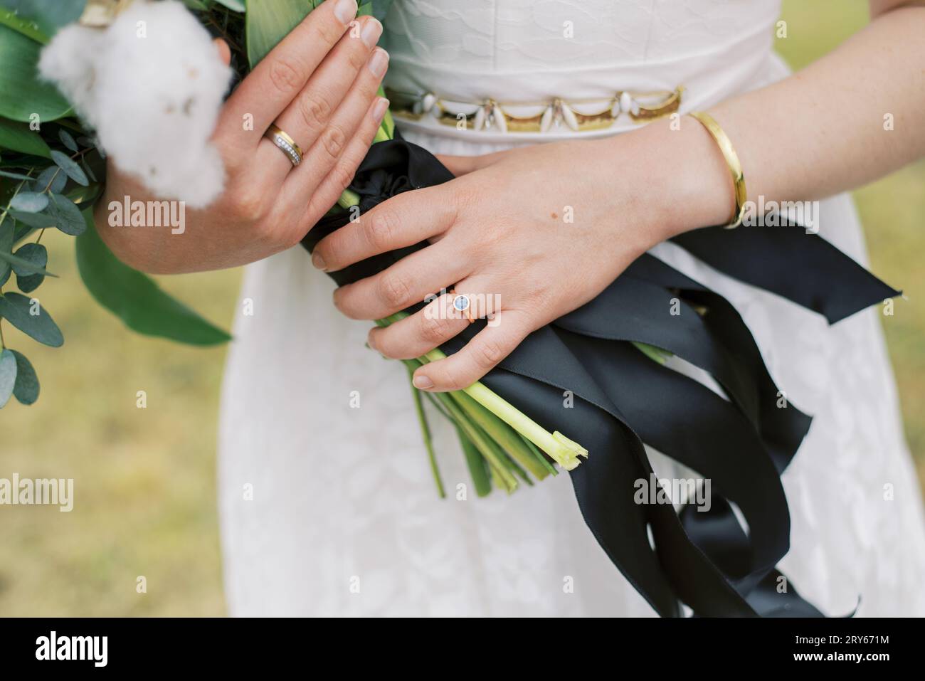 Primo piano delle mani della sposa con gioielli d'oro, uomini d'ingaggio in pietra blu Foto Stock