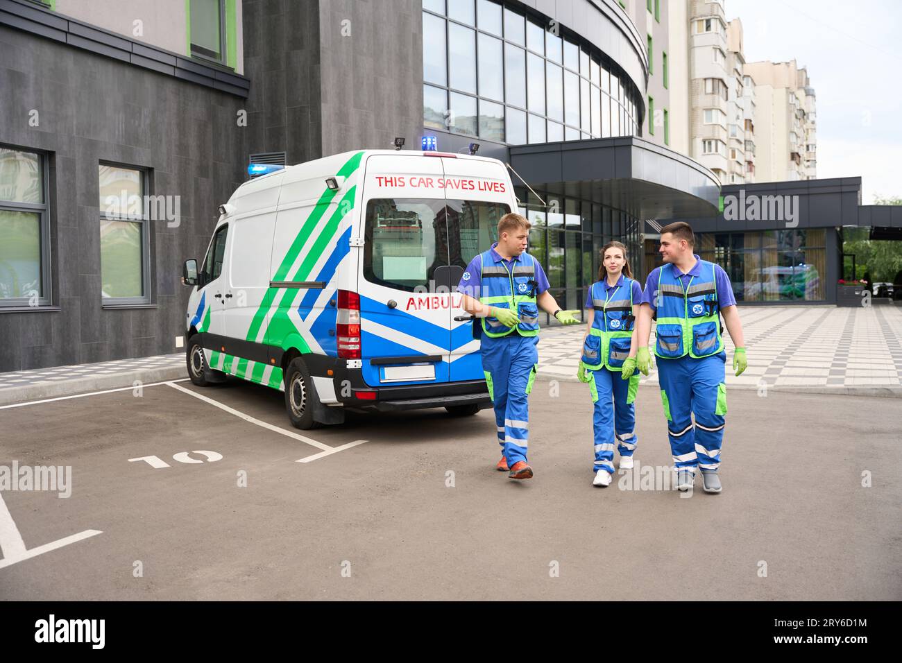 Le persone in uniforme medica camminano lungo il parcheggio vicino all'edificio moderno Foto Stock
