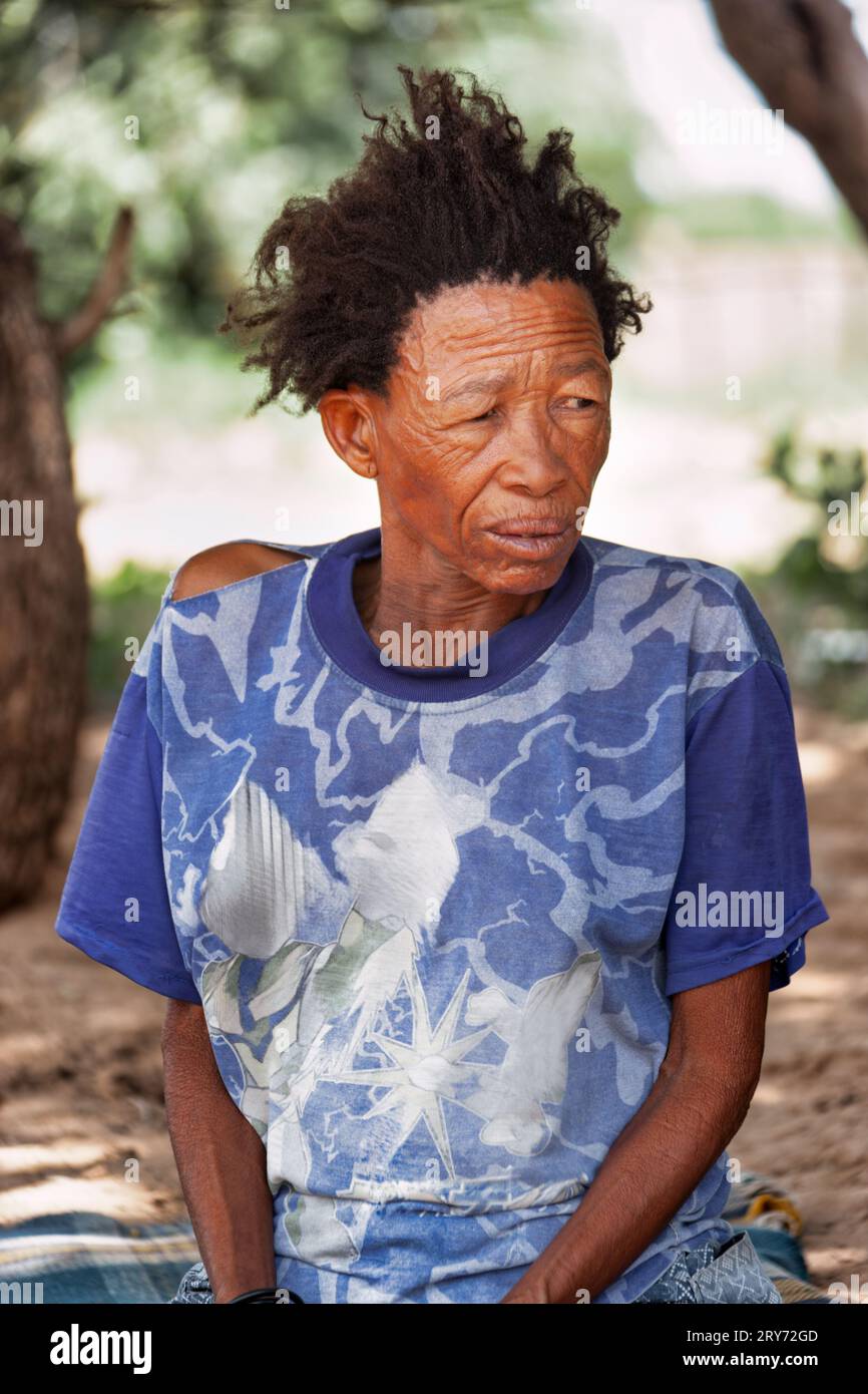 Una vecchia donna di san boscimani del Kalahari centrale, villaggio di New Xade in Botswana, nel cortile della casa dopo il trasferimento Foto Stock
