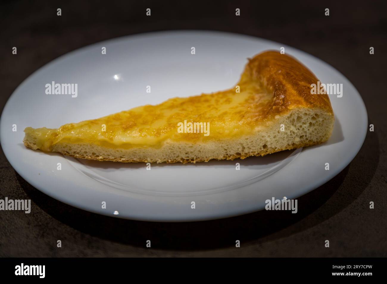 Una fetta di una specialità di Friburgo si trova su un piatto: una pasta piatta con una crosta dorata e un ripieno giallo cremoso, fotografata a Friburgo, Svizzera. Foto Stock