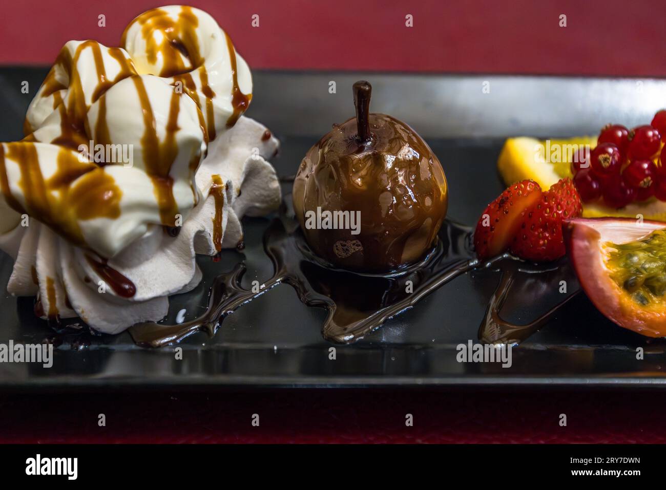Meringues con panna montata al Greyerzer, condite con vin cuit, vengono servite insieme a una pera glassata scura e frutti di bosco freschi come finale dolce di un menù Kilbi nel cantone di Friburgo, Svizzera. Meringues con panna montata e Poires à Botzi AOP (pere ricoperte di ciuffi) chiudono tradizionalmente la specialità del Friburgo, chiamata Bénichon in francese. Foto Stock
