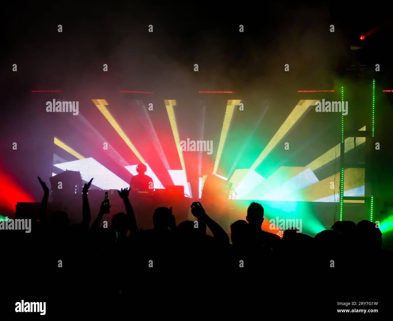 Luci e laser in un nightclub con persone con le mani in alto Foto Stock