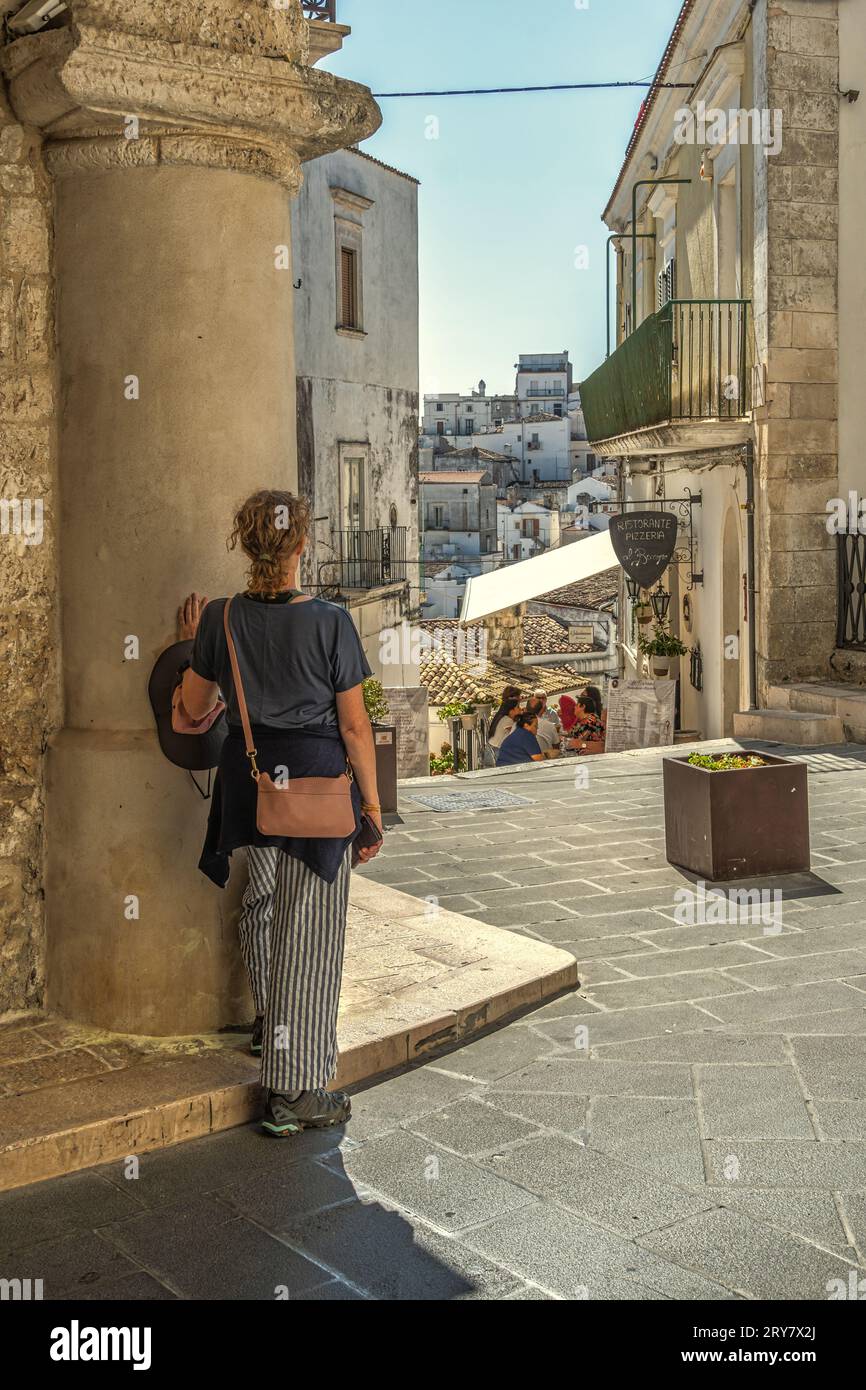 Un turista ammira il paesaggio dei quartieri e delle case bianche tipiche della città di Monte Sant'Angelo. Monte Sant'Angelo, Puglia Foto Stock