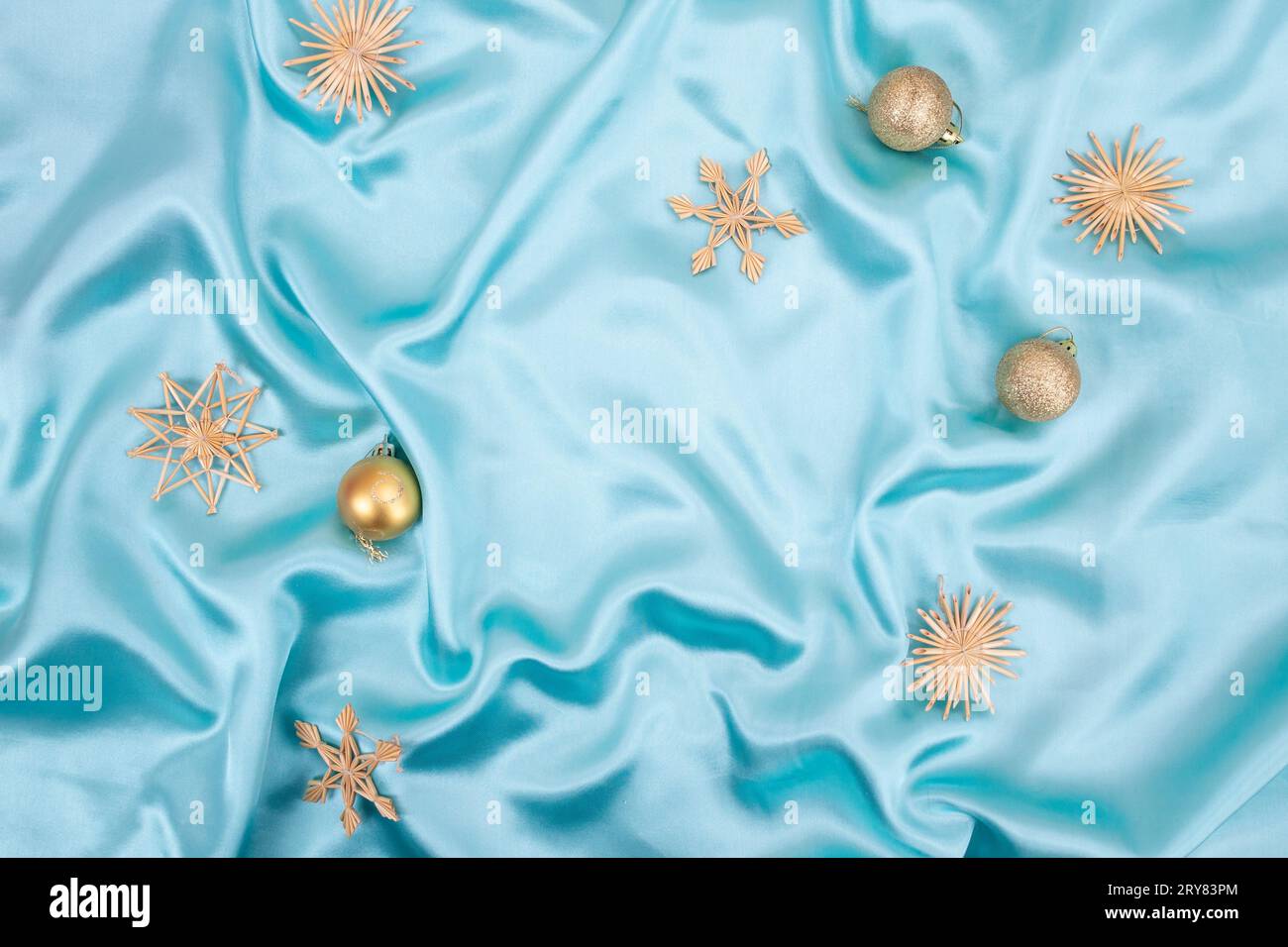 Sfondo in satin turchese con fiocchi di paglia e bauble dorati, sfondo natalizio o Capodanno Foto Stock