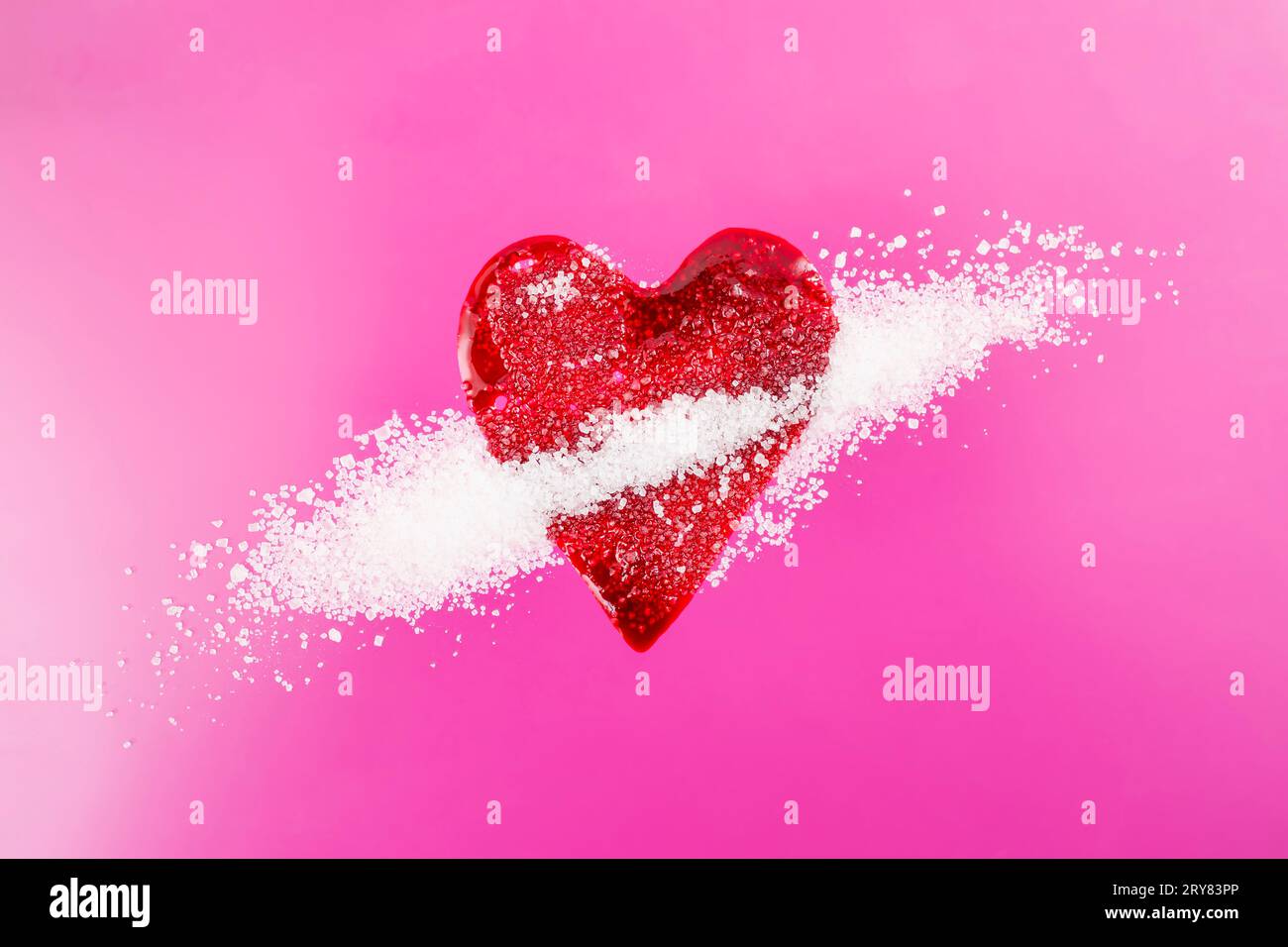 Schizzi di sangue rosso sotto forma di cuore mescolato con cristalli di zucchero su sfondo magenta, messa a fuoco morbida da vicino, concetto di diabete Foto Stock