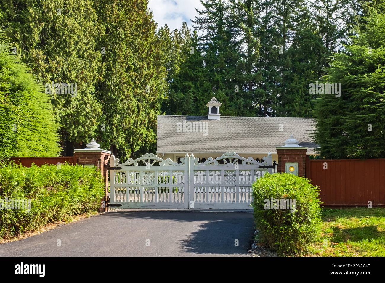 Ingresso recintato con vialetto stradale nella campagna rurale del Canada con recinzione in legno e lussureggianti alberi verdi in estate. Cancelli per una casa di campagna in campagna Foto Stock