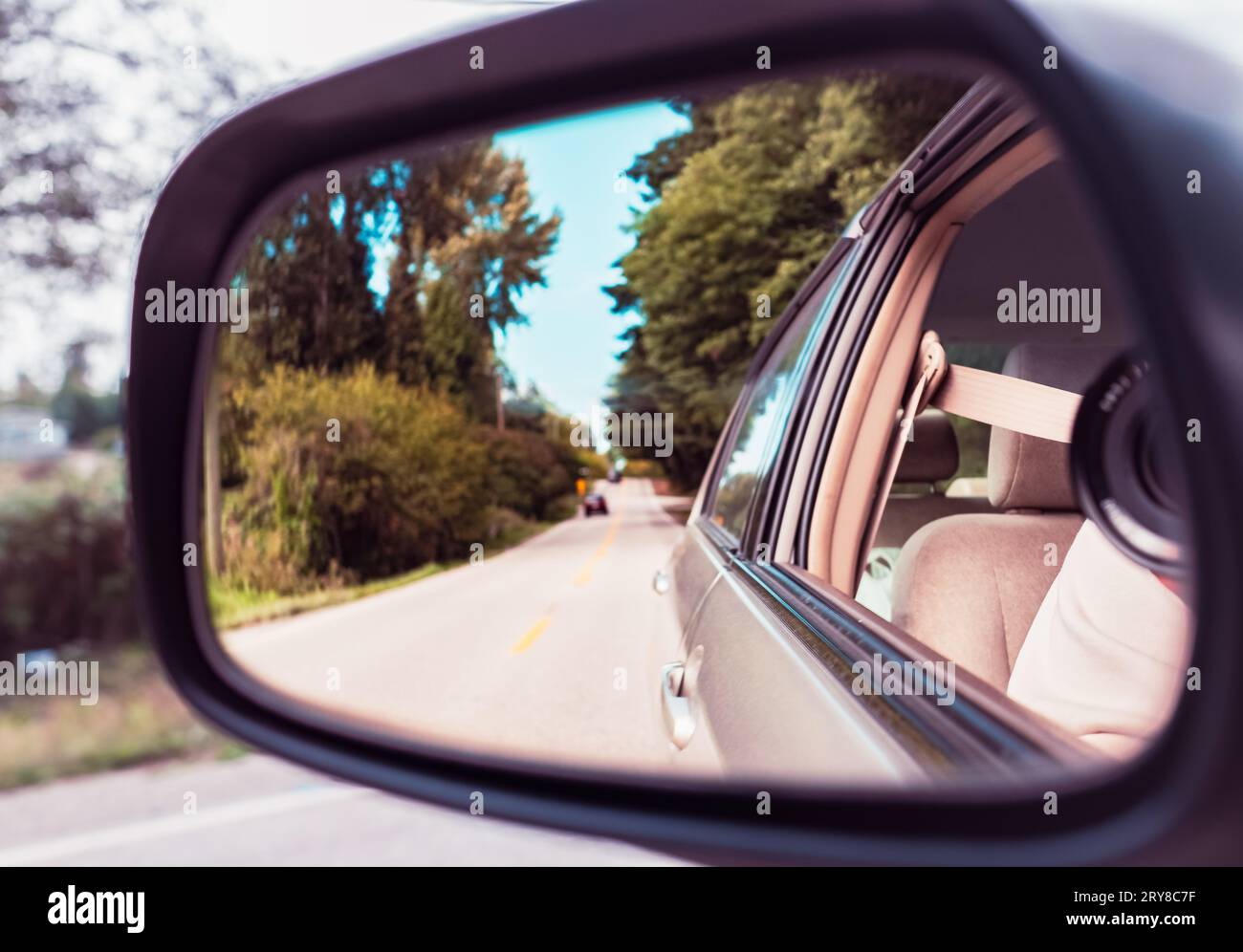 Specchietto retrovisore laterale su un'auto. Riflesso della soleggiata strada autunnale sullo specchio retrovisore laterale della vettura. Guardare nello specchietto retrovisore di un veicolo. Paesaggio nel si Foto Stock
