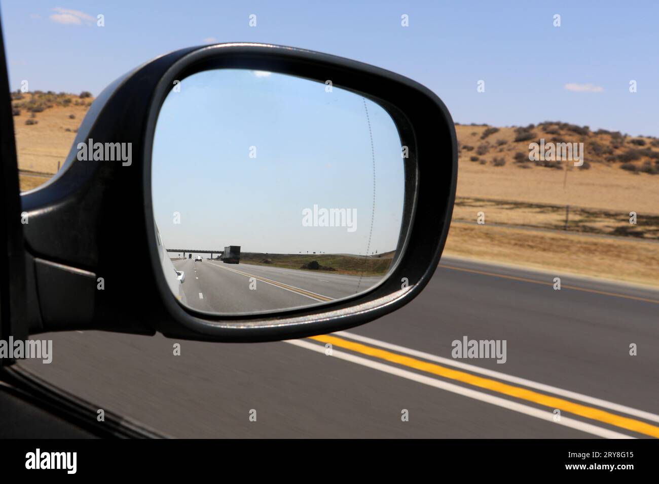 Guardando indietro nello specchietto retrovisore laterale della vettura, guida a destra, punto di vista del conducente Foto Stock