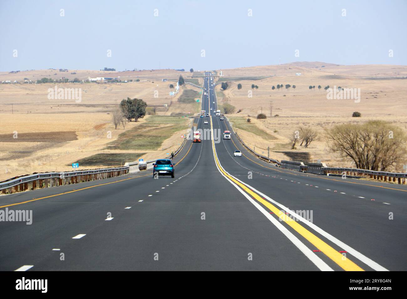 La superstrada N3 tra Durban e Johannesburg, dal punto di vista dei conducenti, fino all'orizzonte con automobili e camion e paesaggi asciutti Foto Stock