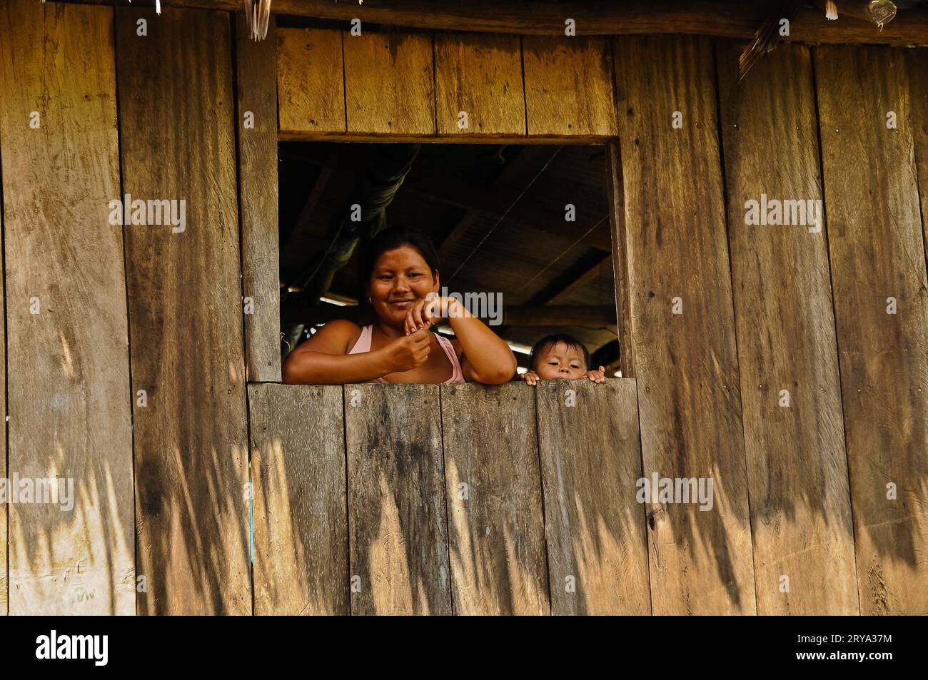 Madre e bambino attraverso il loro spioncino Stilt Hut, villaggio amazzonico, Perù Foto Stock