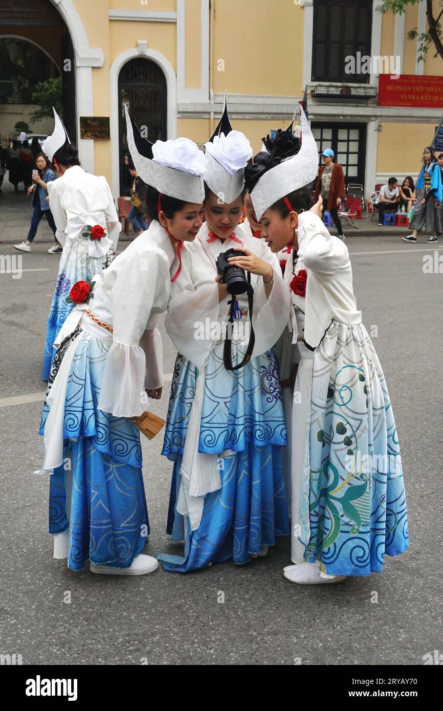 Gli artisti in costume si riuniscono intorno a una macchina fotografica per guardare le foto del loro spettacolo di danza in un festival culturale giapponese nel centro di Hanoi, in Vietnam Foto Stock
