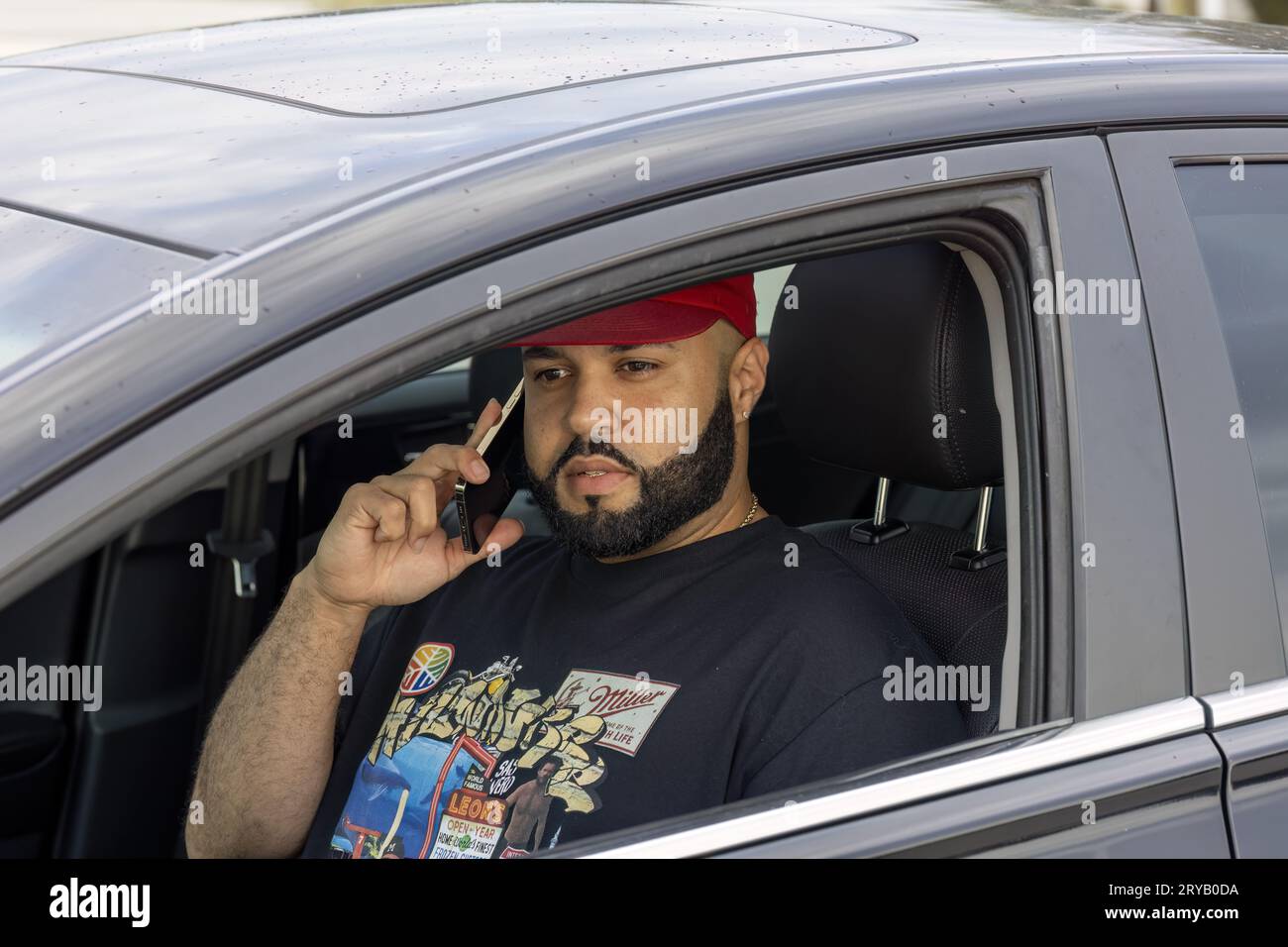 un uomo con la barba che parla al telefono in macchina Foto Stock