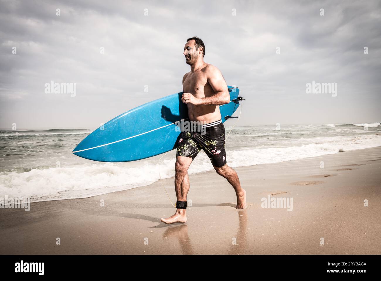 Surfer correre sulla spiaggia Foto Stock