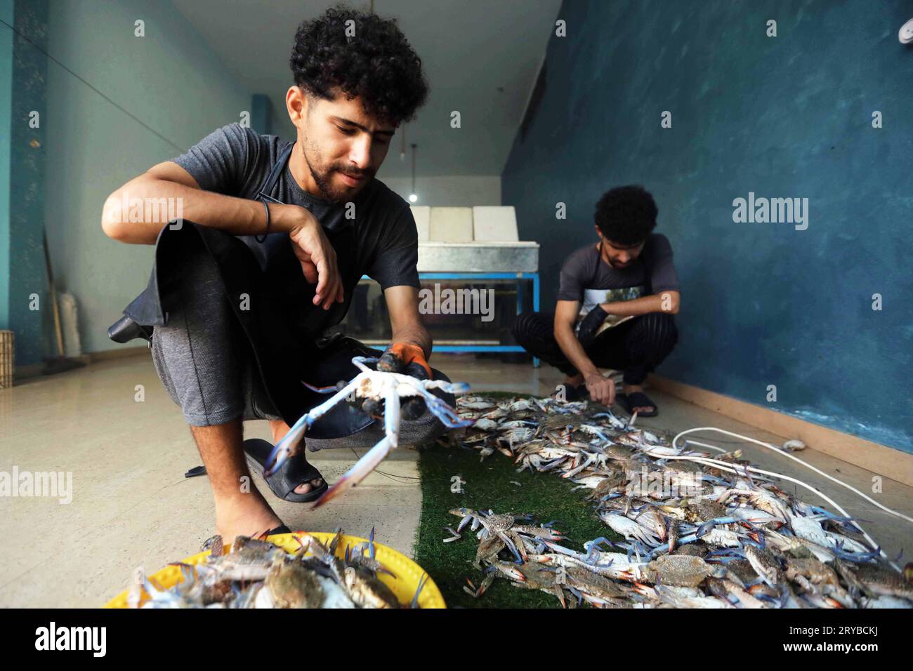 Middle East News/Gaza/territori palestinesi dal pensare all'immigrazione all'apertura di negozi di pesce, i gemelli palestinesi Khamis e Mahmoud Bakr lavorano all'interno del loro negozio, Twin Fish and a Kitchen, nel campo di Nuseirat nella Striscia di Gaza centrale. The Gaza Strip Palestine Copyright: XMahmoudxxAjjourx 101A4379 Credit: Imago/Alamy Live News Foto Stock