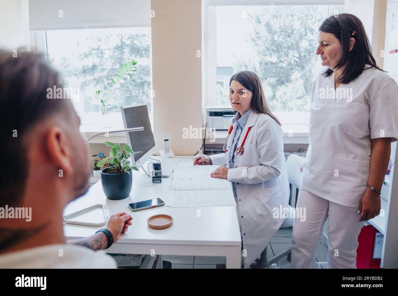 Una clinica ospedaliera occupata con medici che conducono esami approfonditi, controllo della vista, dell'udito e della gola, pulizia delle orecchie, e fornire successo Foto Stock