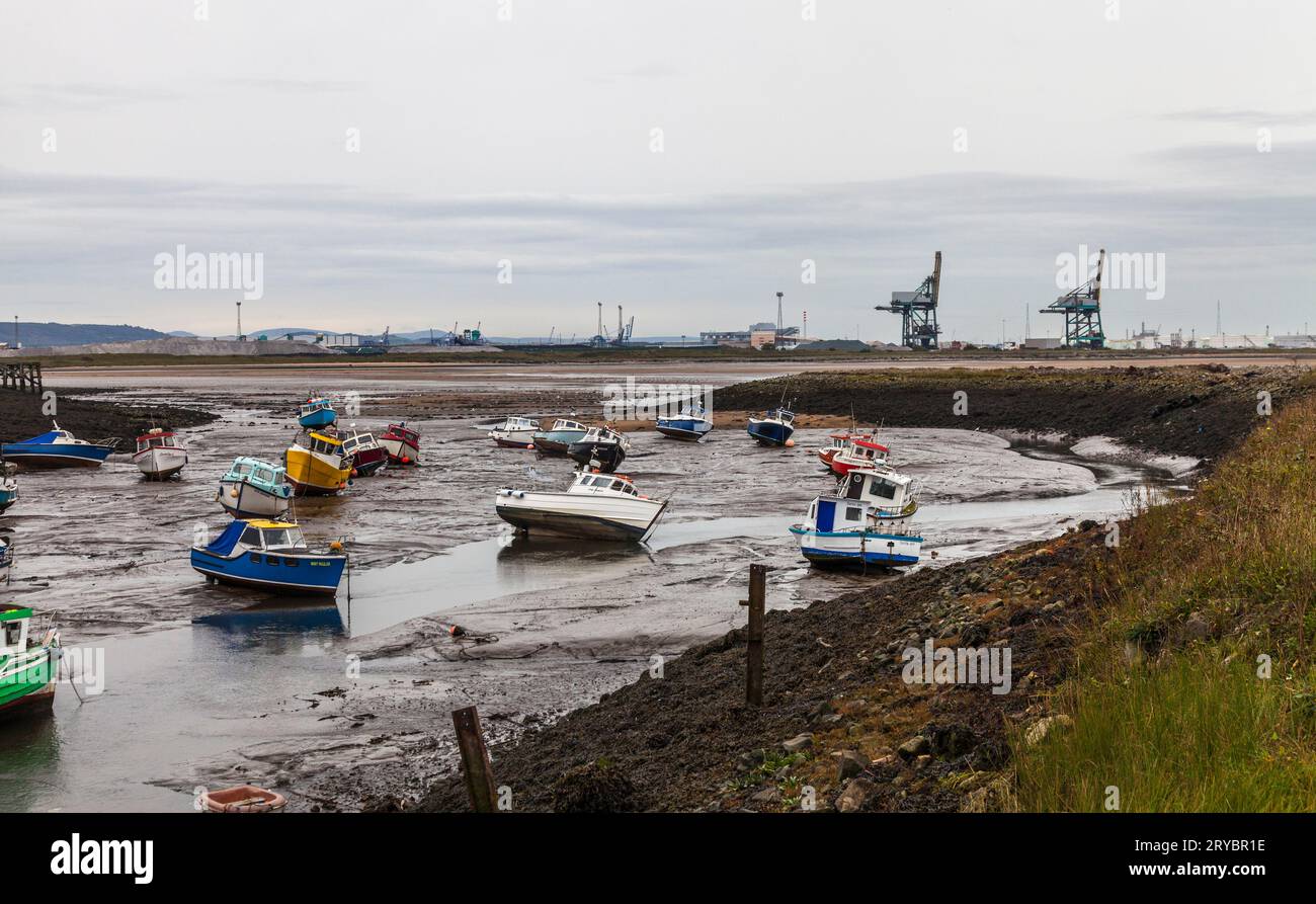 Barche ormeggiate nel porto di Paddys Hole, Redcar, Inghilterra, Regno Unito con Teesport industriale sullo sfondo. Bassa marea Foto Stock