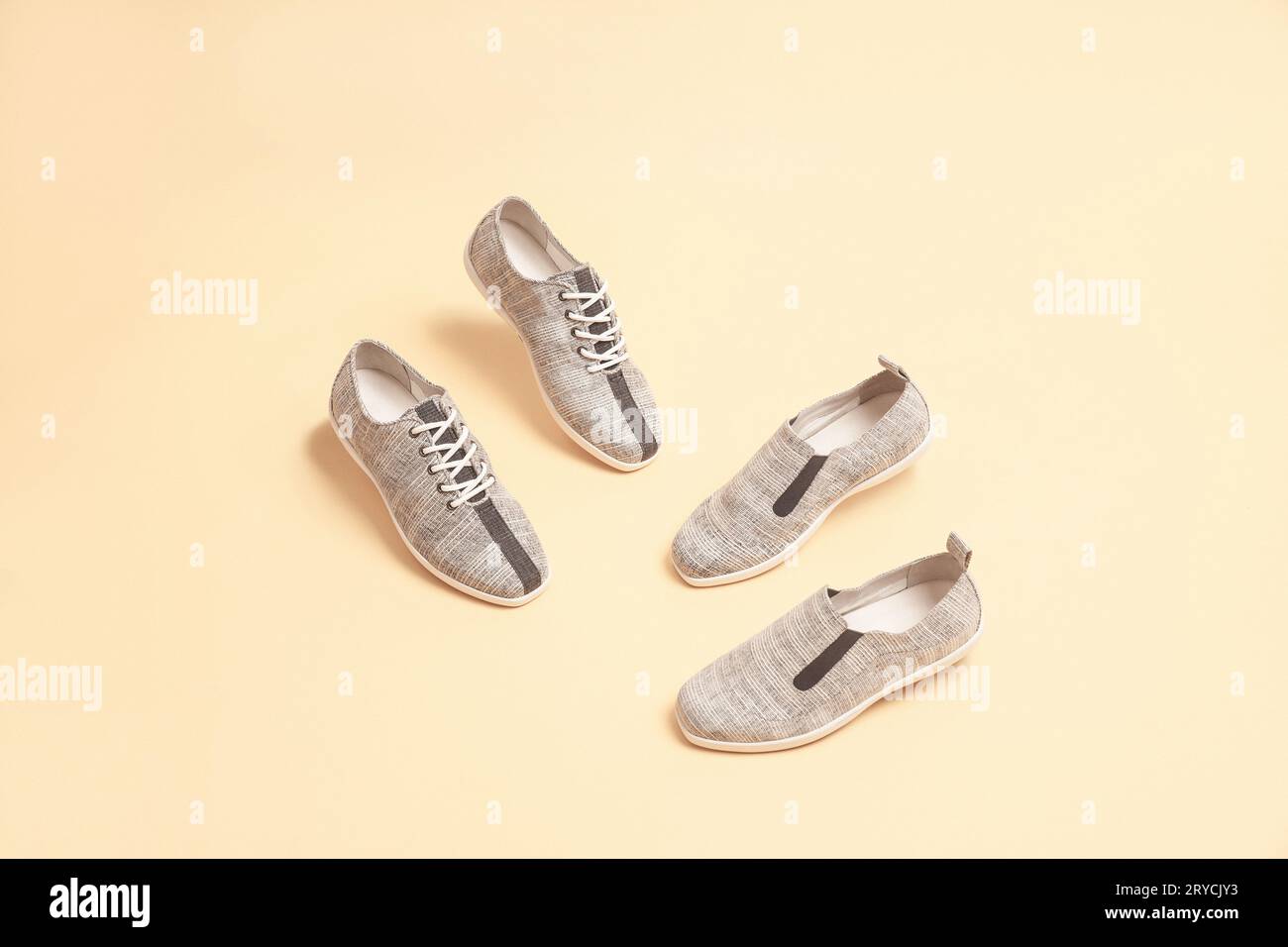 Eleganti sneaker di colore grigio isolate su sfondo beige; spazio per il testo; vista in prospettiva Foto Stock