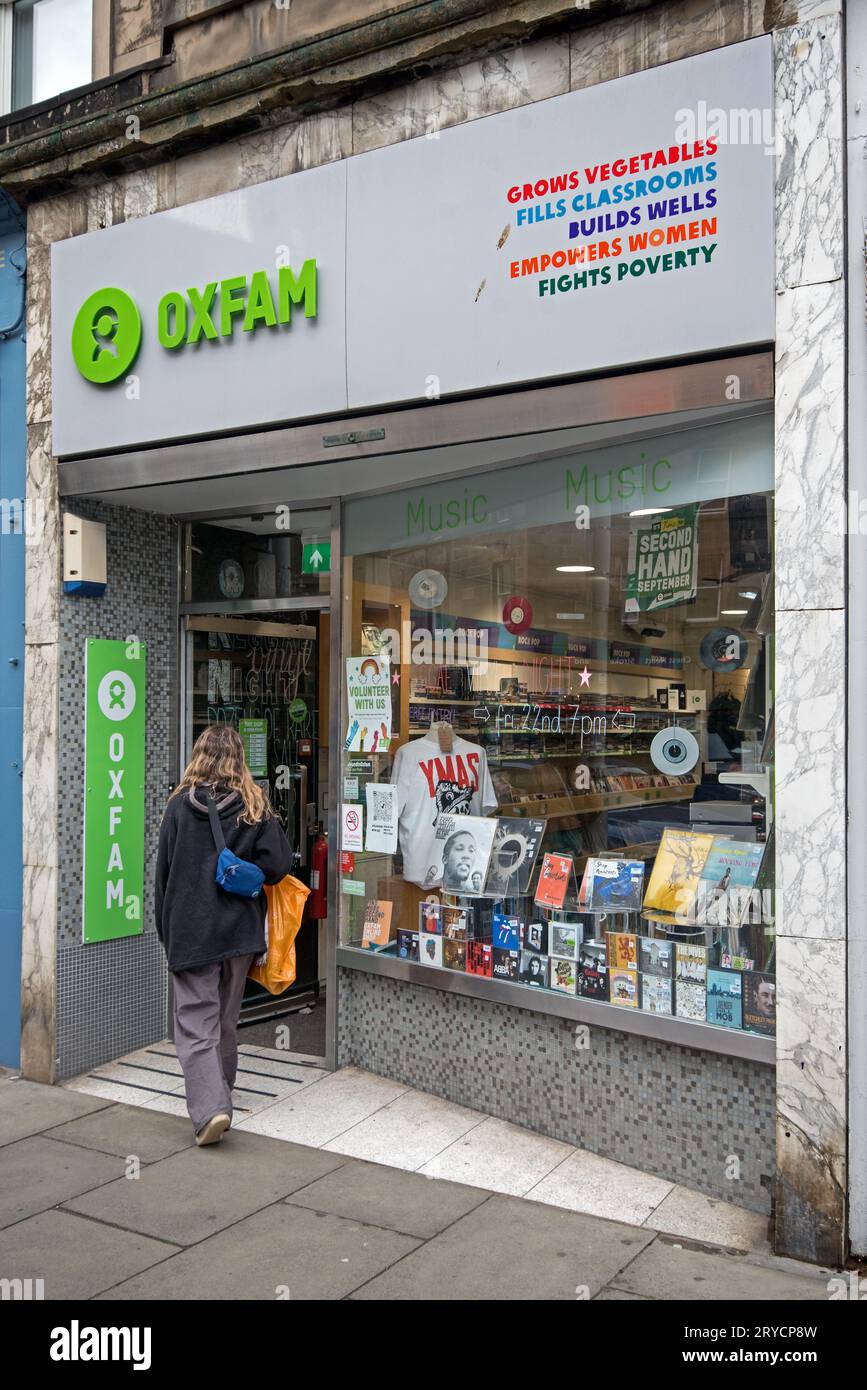 Giovane donna che cammina in un negozio di musica Oxfam a Stockbridge, Edimburgo, Scozia, Regno Unito. Foto Stock