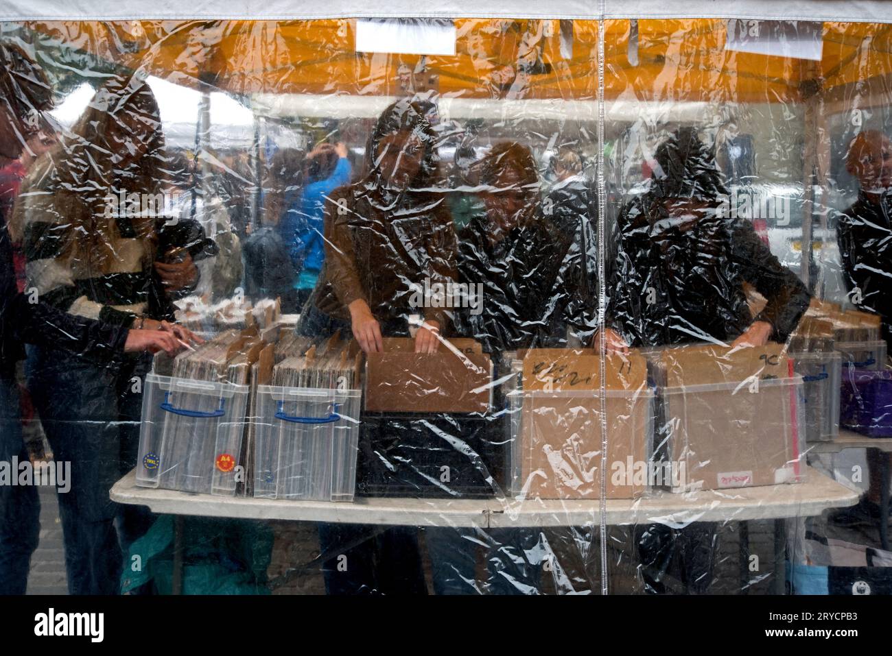 I clienti che sfogliano i dischi in vinile in una bancarella di dischi all'aperto a Grassmarket, Edimburgo, Scozia, Regno Unito, hanno fotografato con fogli di plastica. Foto Stock