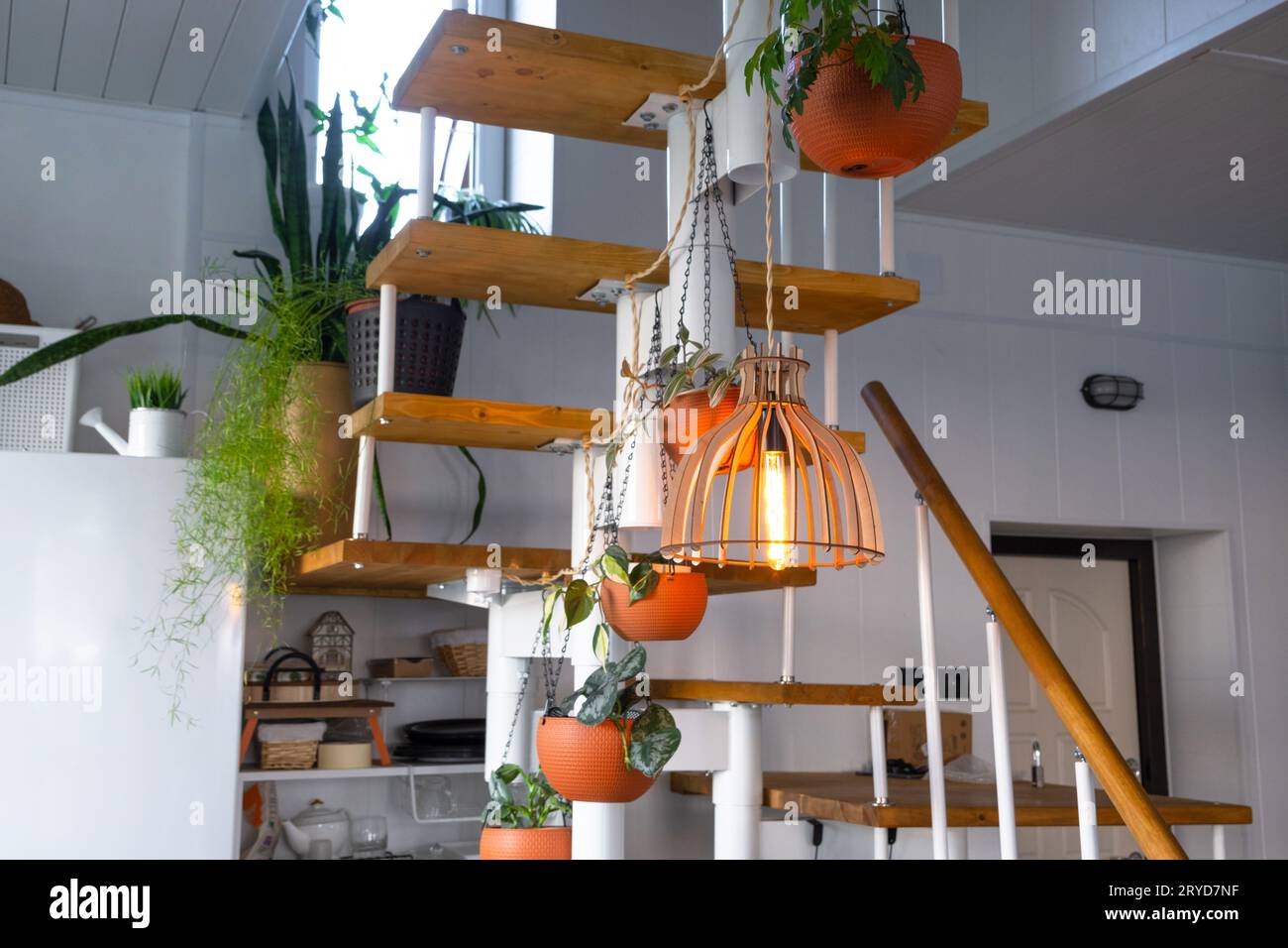 Scala modulare in metallo con gradini in legno all'interno bianco di una casa verde con piante in vaso, vaso di fiori appeso, paralume Foto Stock