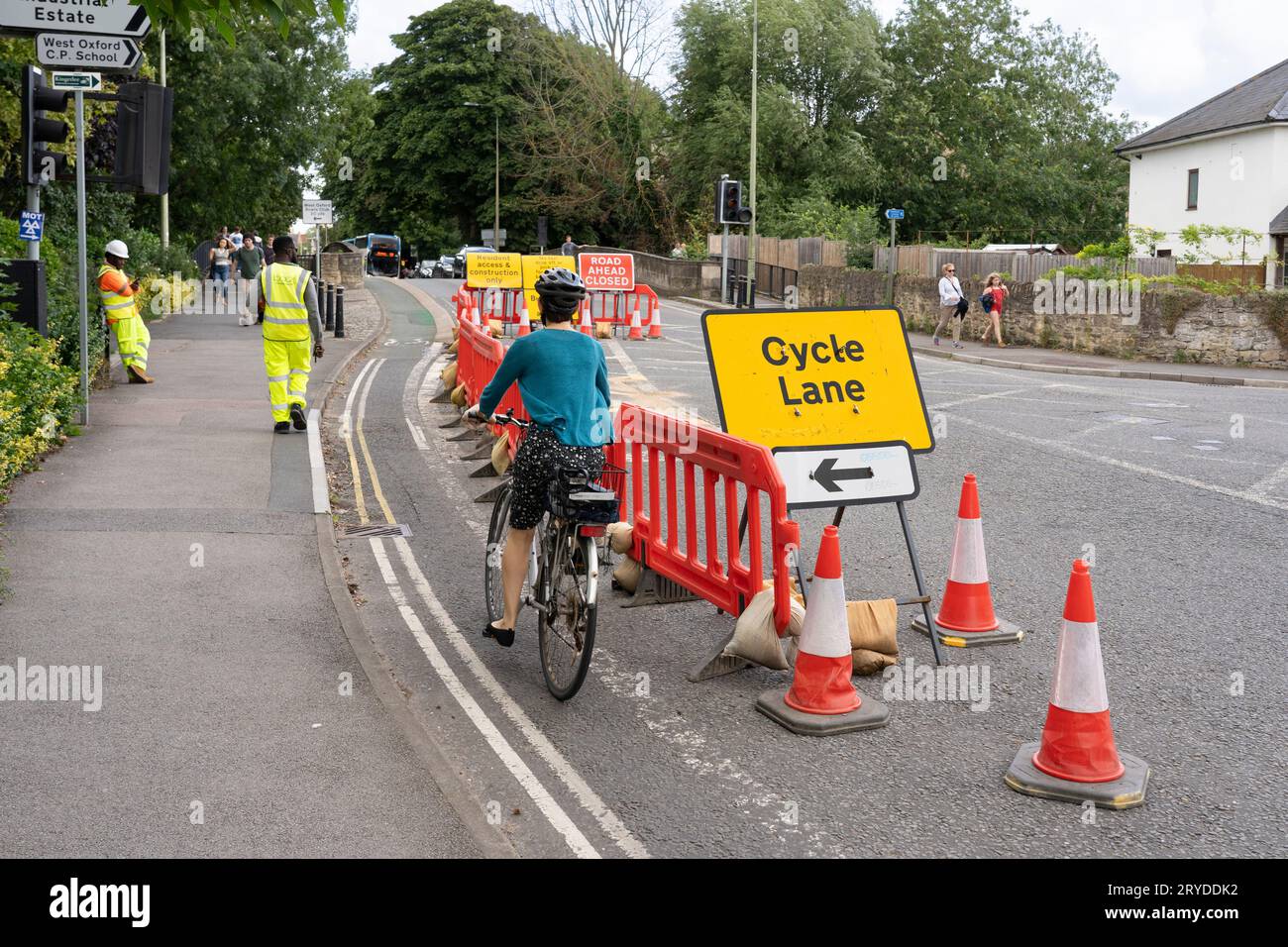 Una ciclista donna che indossa un casco sulla A420 Botley Road a Oxford, pedalando lungo una pista ciclabile temporanea a causa di lavori stradali. Estate 2023, Inghilterra Foto Stock