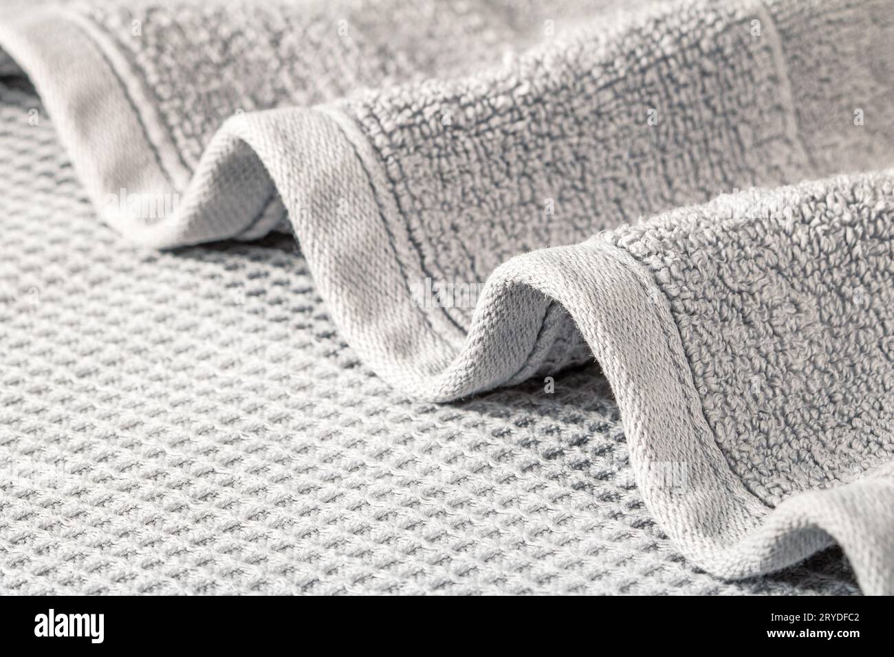 Asciugamano morbido in spugna piegato a onde su sfondo grigio in primo piano. Foto Stock