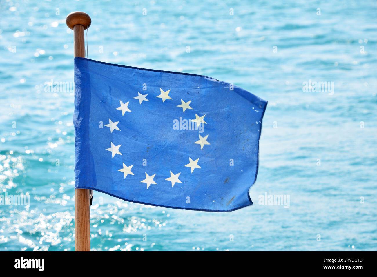 Primo piano bandiera dell'UE che sventola in vento sull'acqua di mare Foto Stock
