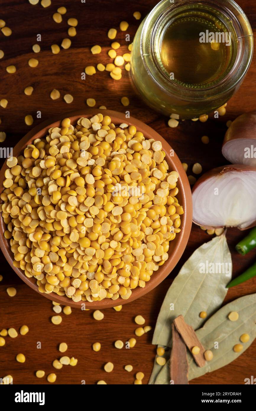 Un recipiente di terra pieno di piselli daal-piccione circondato da olio in contenitore di vetro, cipolla tagliata a fette, peperoncini verdi, alloro secco e cannella Foto Stock