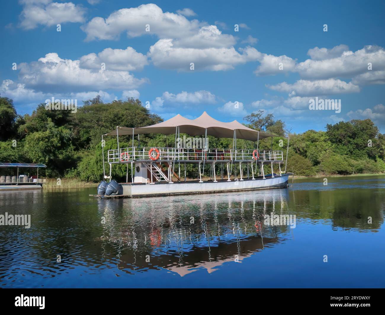 Delta dell'Okavango in Botswana, grande barca a motore all'ombra che trasporta i turisti attraverso i canali Foto Stock