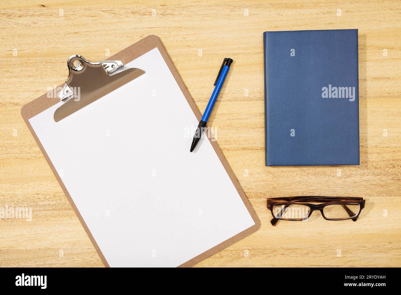 Area di lavoro con clip board vuota, penna, occhiali e diario su tavolo di legno Foto Stock