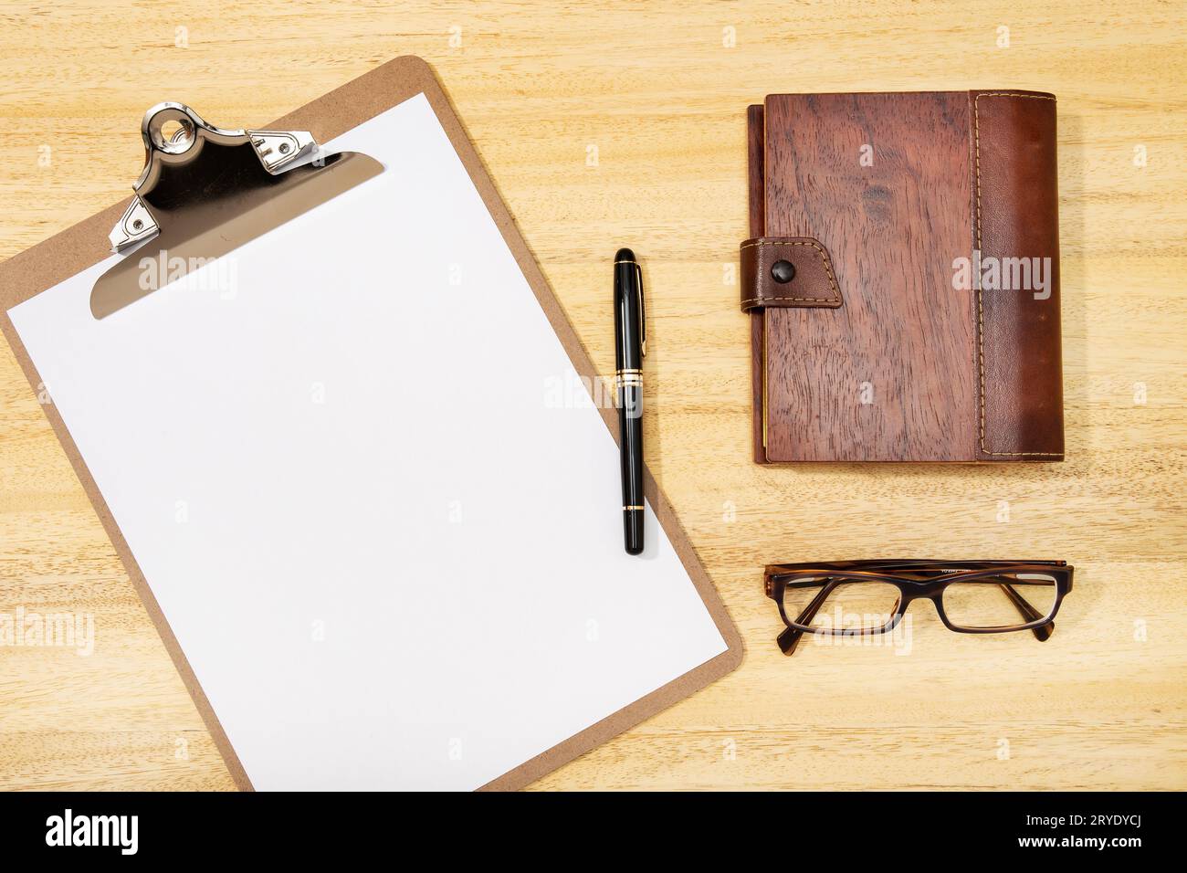 Area di lavoro con clip board vuota, penna, occhiali e diario su tavolo di legno Foto Stock