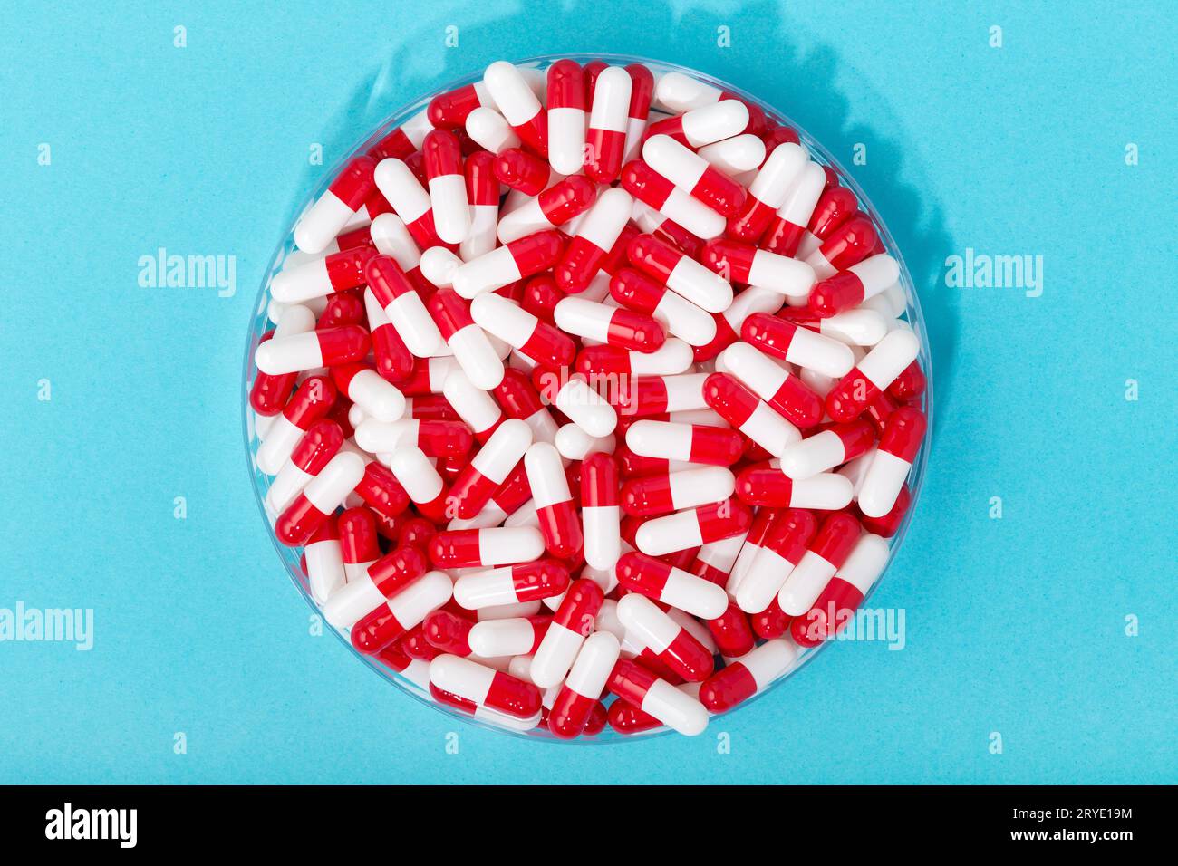 Gruppo di capsule pillole in contenitore rotondo su sfondo blu Foto Stock