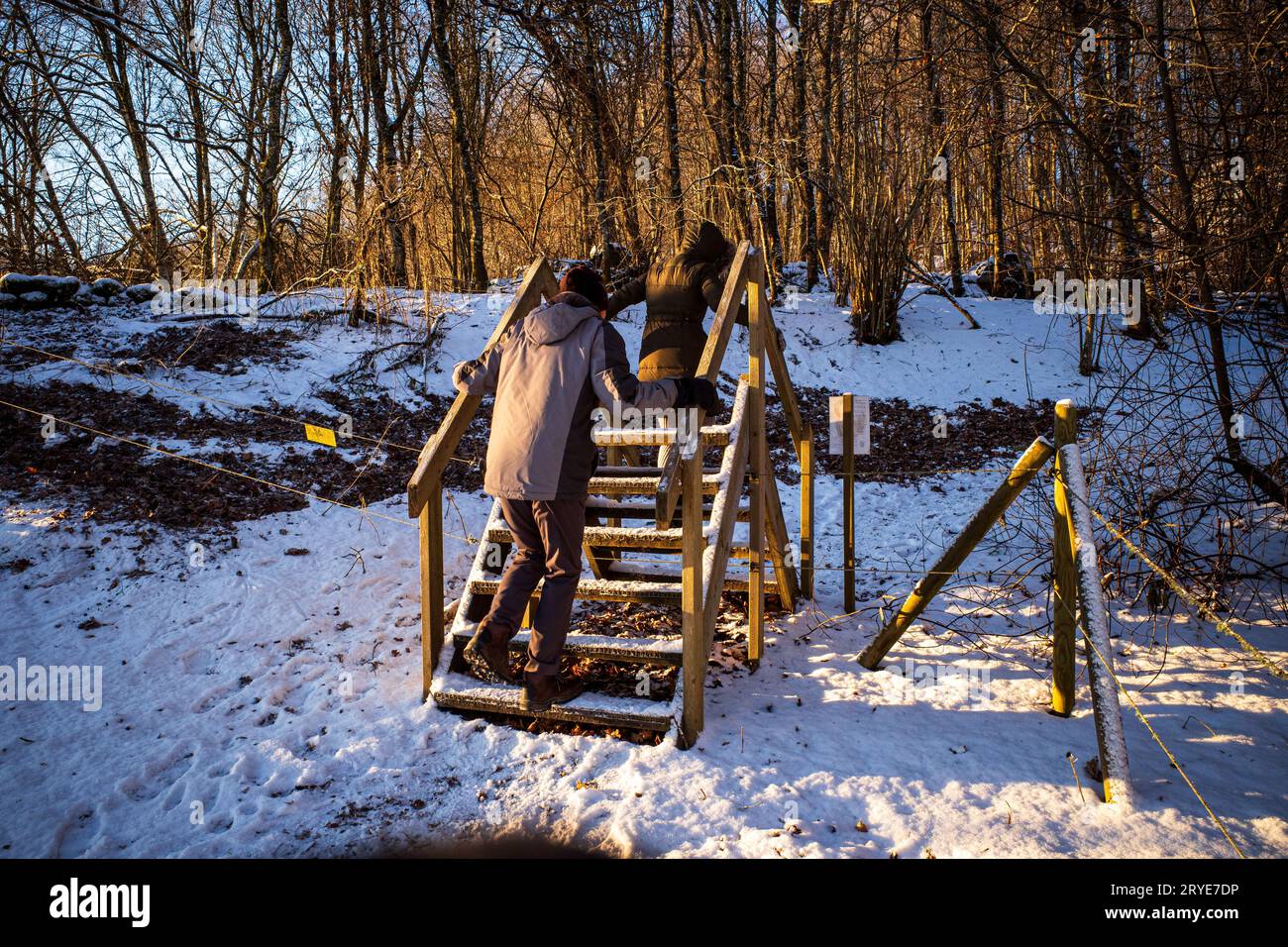 Un paio di passeggiate lungo gradini di legno in un paesaggio invernale innevato, crogiolandosi nella calda luce del sole. Foto Stock