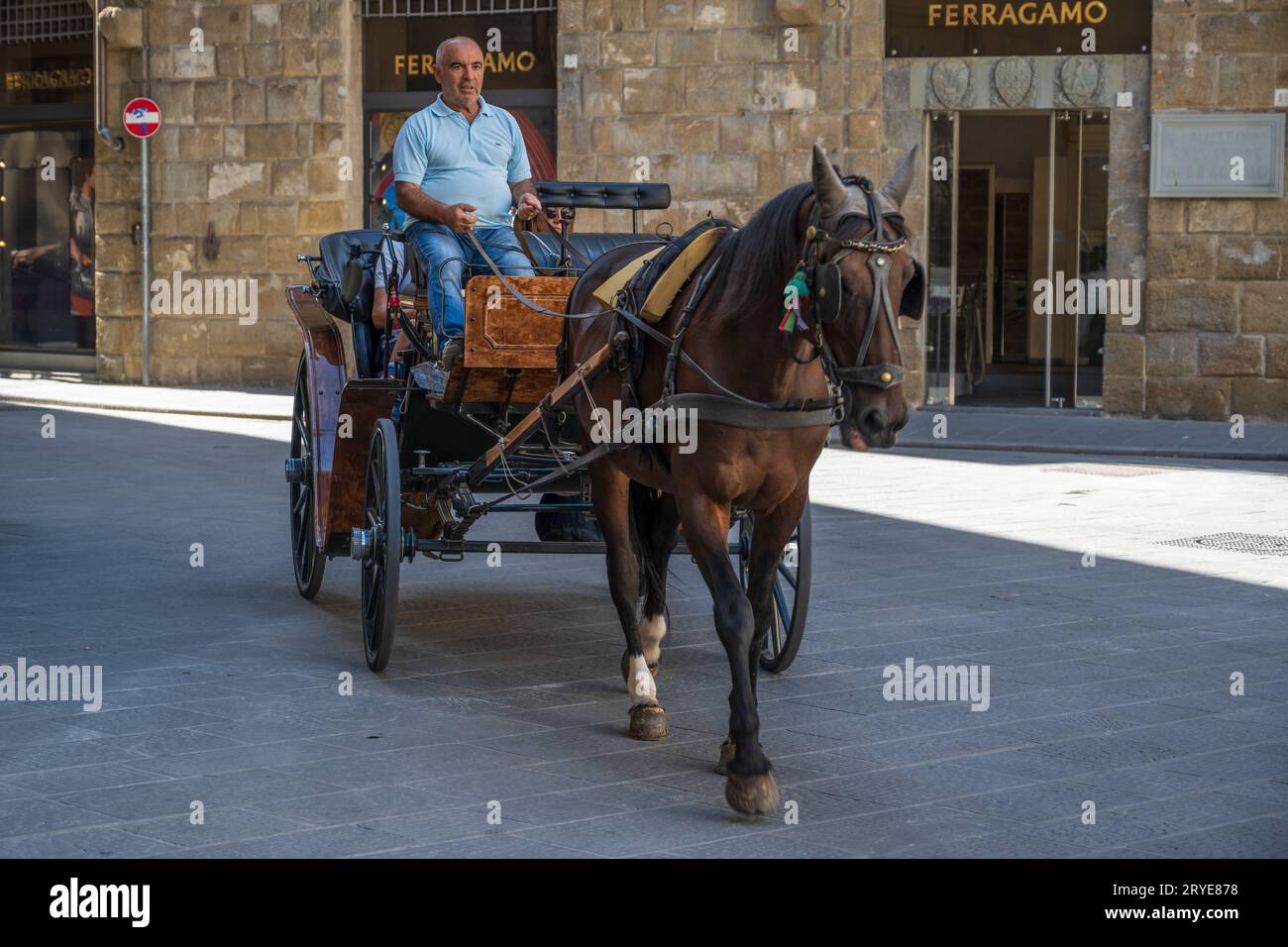 Firenze, Italia - 2 settembre 2023. Un autista con due passeggeri a bordo naviga su un cavallo e una carrozza attraverso un elegante quartiere commerciale di Floren Foto Stock