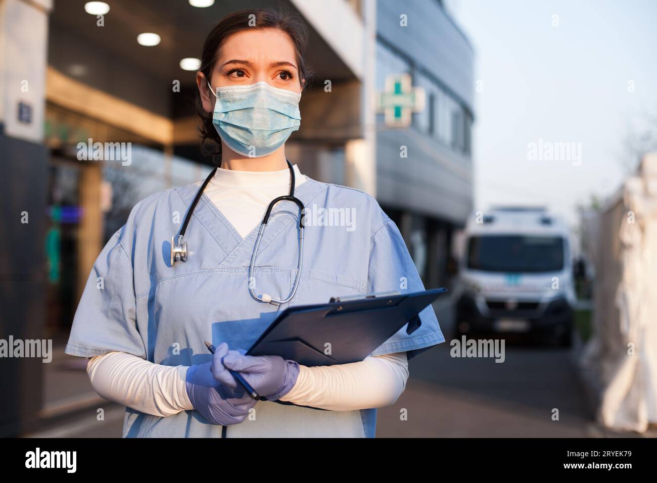 Giovane medico femminile di fronte a servizi di emergenza ambulanza o ospedale Foto Stock