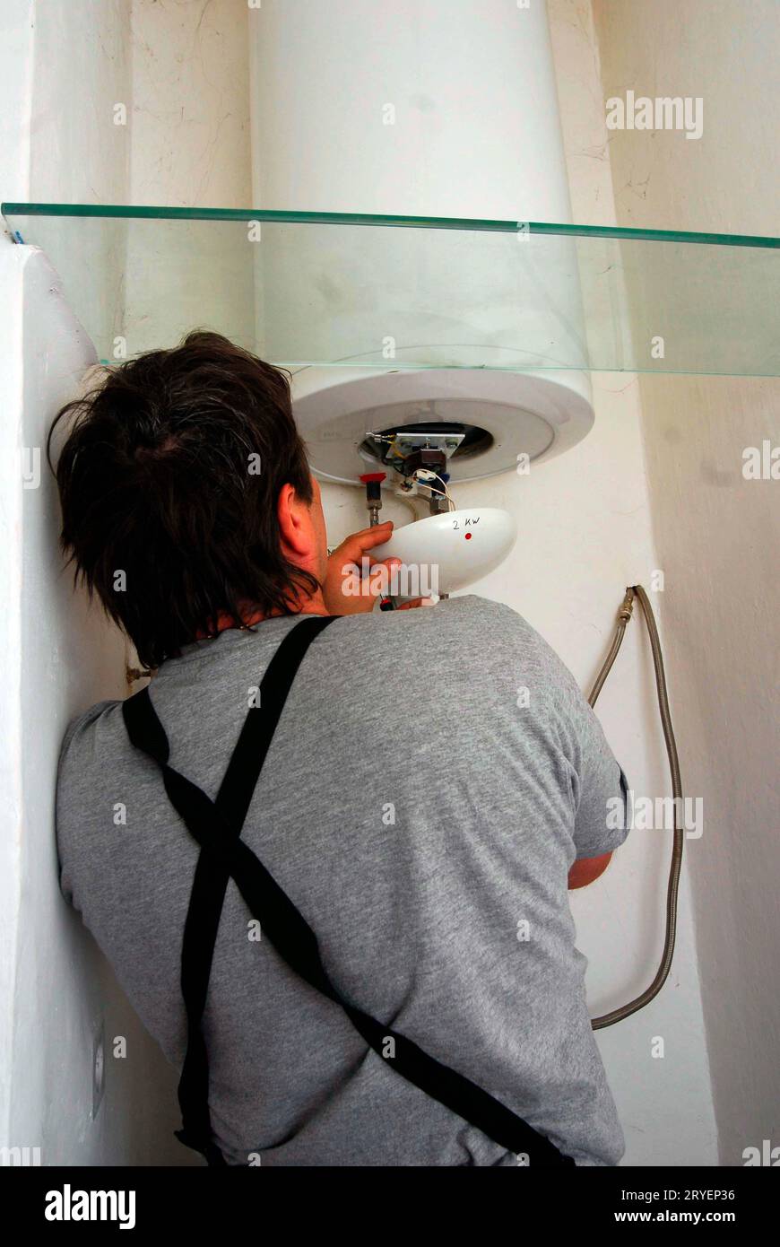 Elettricista che ripara uno scaldacqua Foto Stock