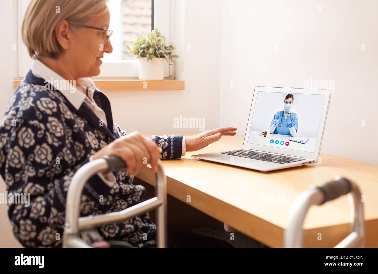 Anziana donna anziana in pensione con problemi di mobilità che parla con il medico del GP del Regno Unito tramite una videochiamata virtuale di telemedicina Foto Stock