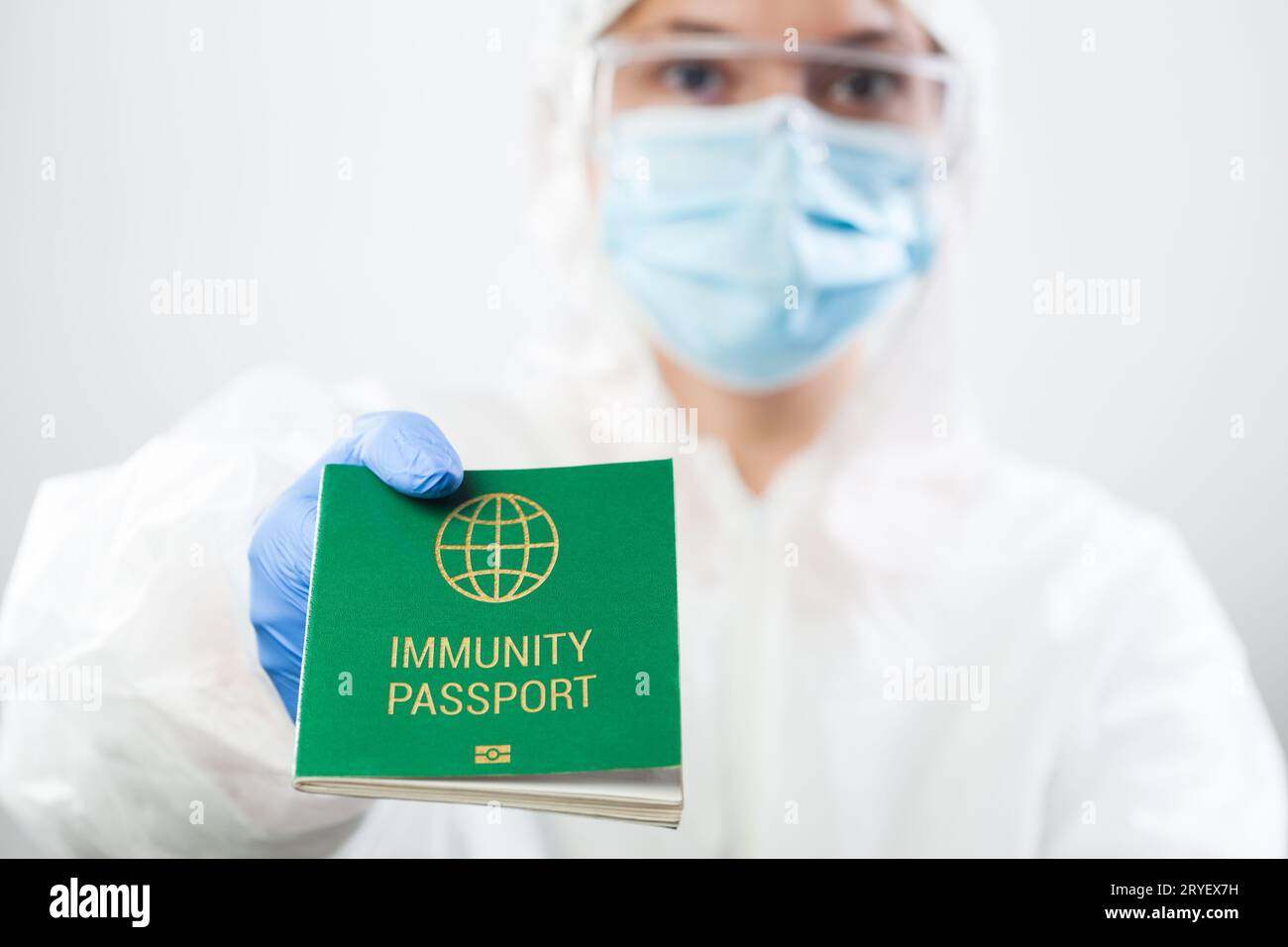 Medico UK operatore sanitario addetto alla sicurezza in dispositivi di protezione personale in possesso di passaporto di immunità verde carta d'identità Foto Stock