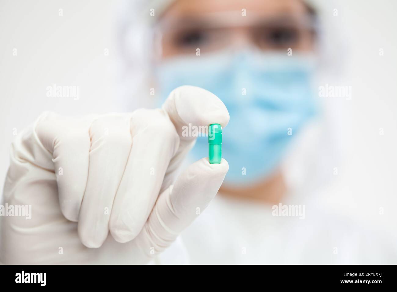 Farmacista donna che indossa dispositivi di protezione individuale (DPI) con pillola verde Foto Stock