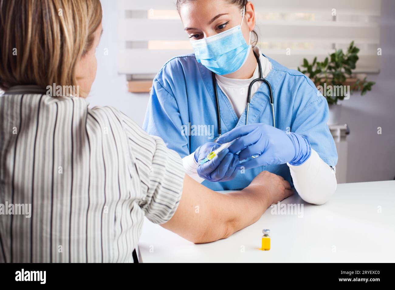 Giovane medico donna che vaccina pazienti anziani nell'ufficio del GP del Regno Unito Foto Stock