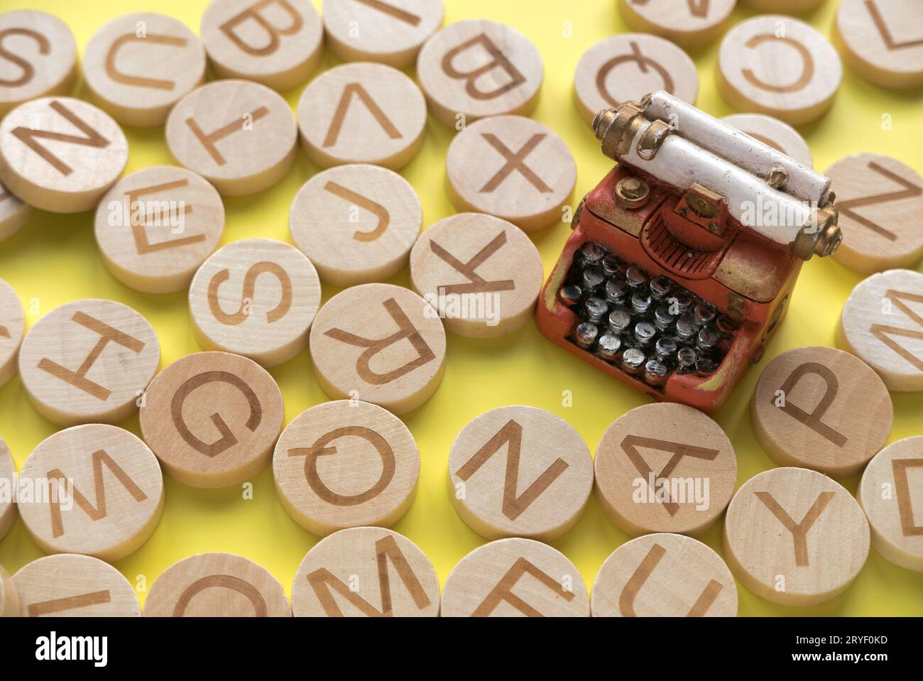 Concetto di apprendimento dell'inglese, ricerca di parole e informazioni. Lettera alfabetica inglese e macchina da scrivere in miniatura su sfondo giallo. Foto Stock