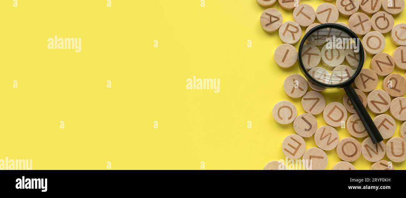 Concetto di apprendimento dell'inglese, ricerca di parole e informazioni. Lettera alfabetica inglese e lente di ingrandimento. Sfondo giallo con spazio di copia. Foto Stock