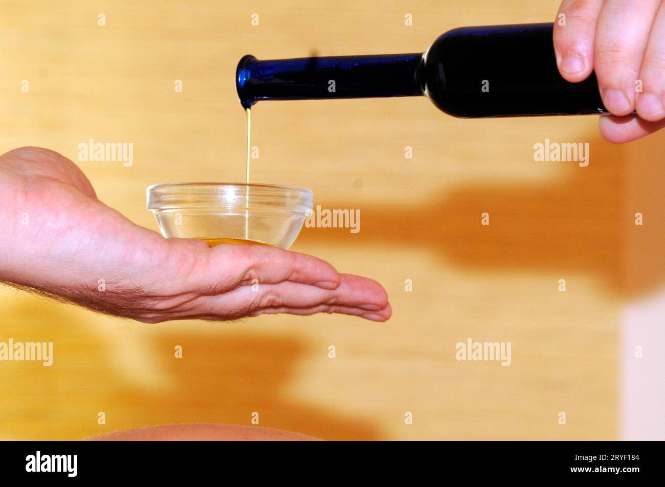 Versare l'olio per massaggi in un recipiente piccolo Foto Stock