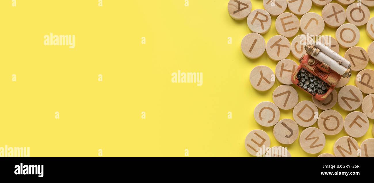Concetto di apprendimento dell'inglese, ricerca di parole e informazioni. Lettera alfabetica inglese e macchina da scrivere in miniatura su sfondo giallo con spazio di copia Foto Stock