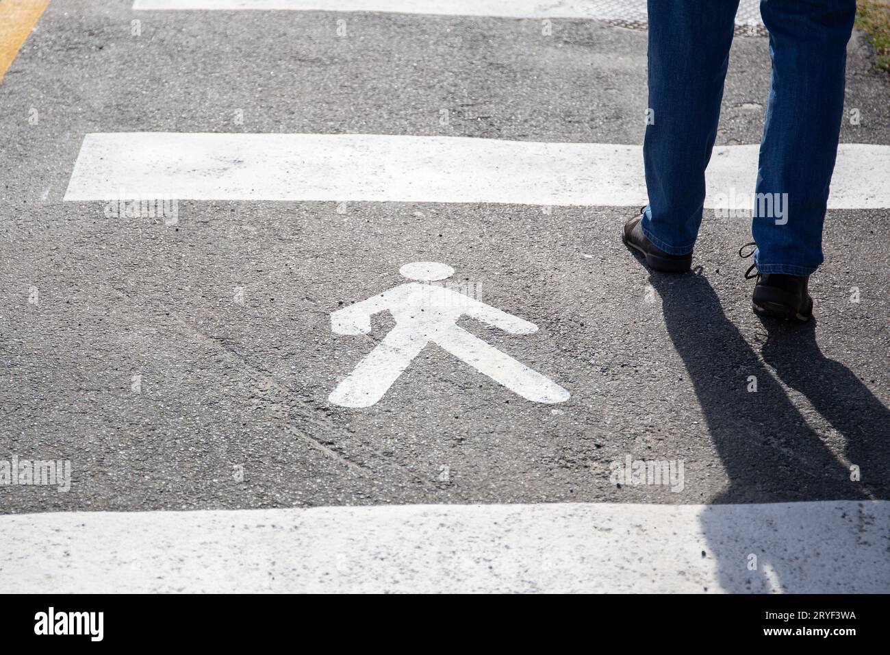 Cartello pedonale sull'asfalto e le gambe umane che camminano in giornata di sole Foto Stock