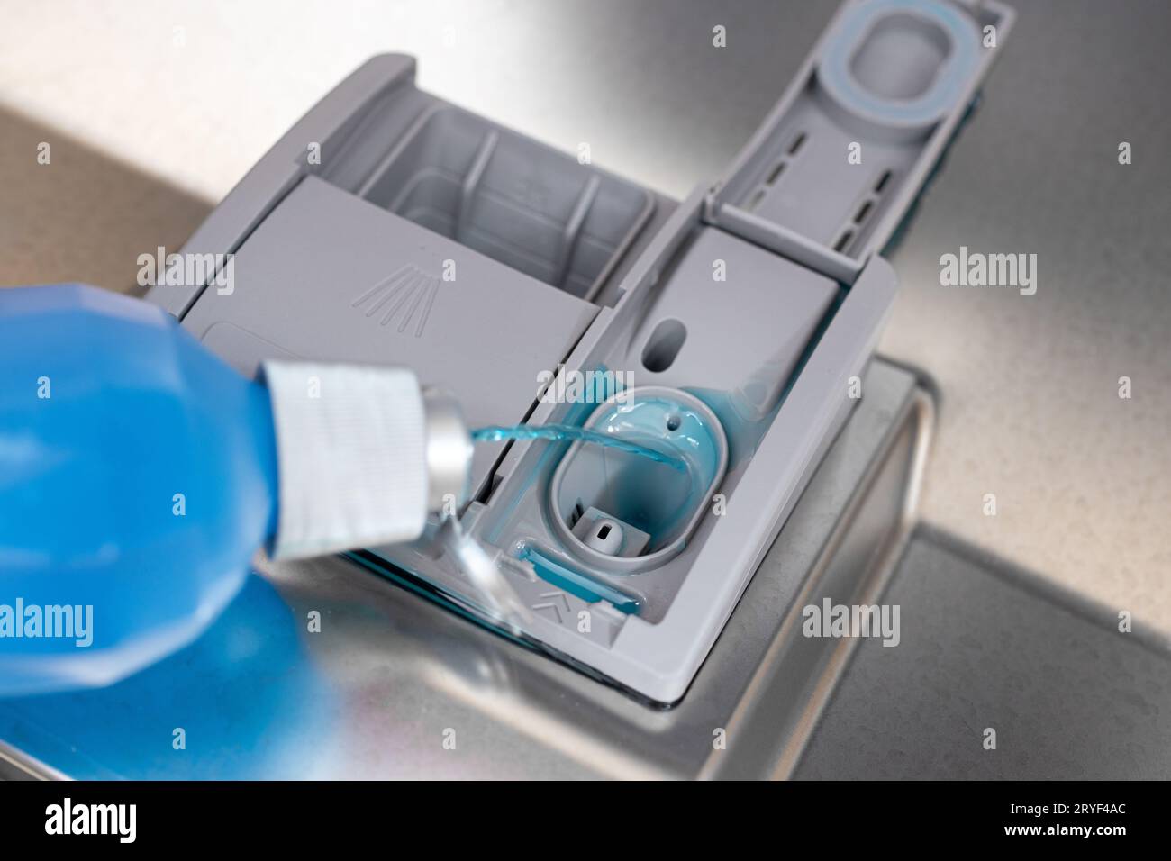 Primo piano del flacone versando il liquido di brillantante in lavastoviglie Foto Stock